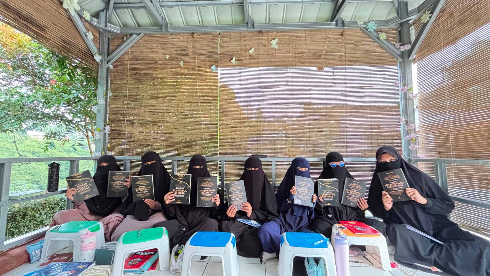 Santriwati berbaris duduk di meja-meja kecil dengan mushaf di hadapan masing-masing